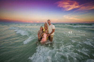 W family laughs together at the Destin shoreline as gentle waves roll in at sunset