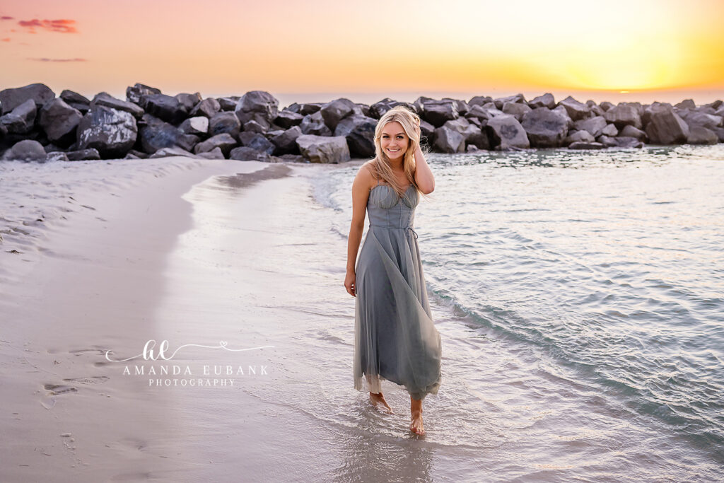 Contemplative profile of senior Miss C in a blue floral toile dress as the Destin Jetties sunset glows behind her