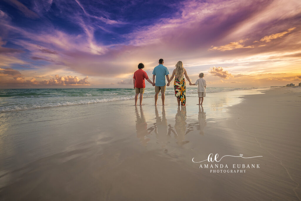 Destin family photographer captures the Willis four in a relaxed standing portrait under a watercolor sky.