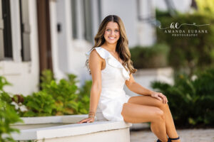Sunset senior portrait of Miss L captured in a relaxed standing pose against the layered courtyard backdrop in Alys Beach.