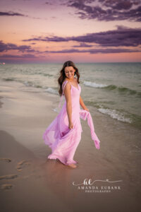 Sunset senior portrait of Miss L standing in the shallow surf with the silk skirt drifting outward in Alys Beach, FL.