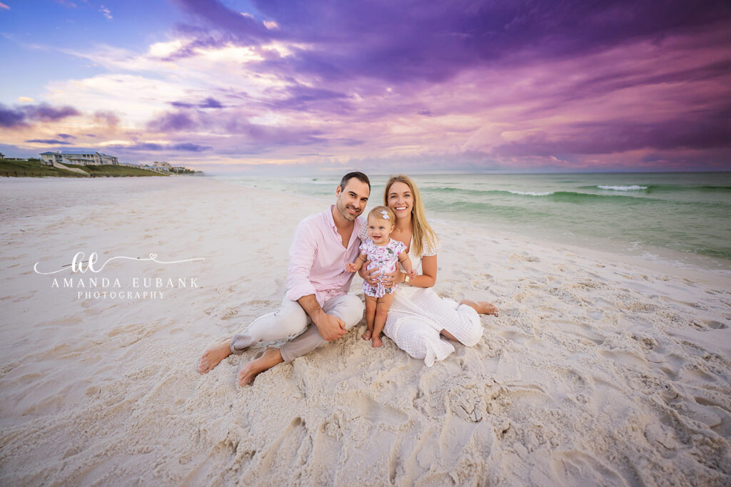 Seaside sunset family portrait of the Schonter Family — Mom holding her baby close as gentle waves whisper at the shore.