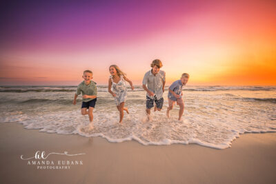 Joyful candid of four Olsen siblings running through the Dune Allen surf under a painted purple sunset.