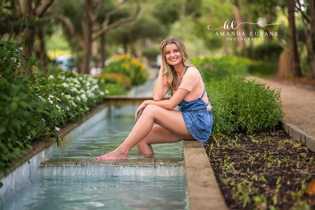 Senior portrait of Lauren in denim overalls barefoot at the Watercolor, FL lily pond.