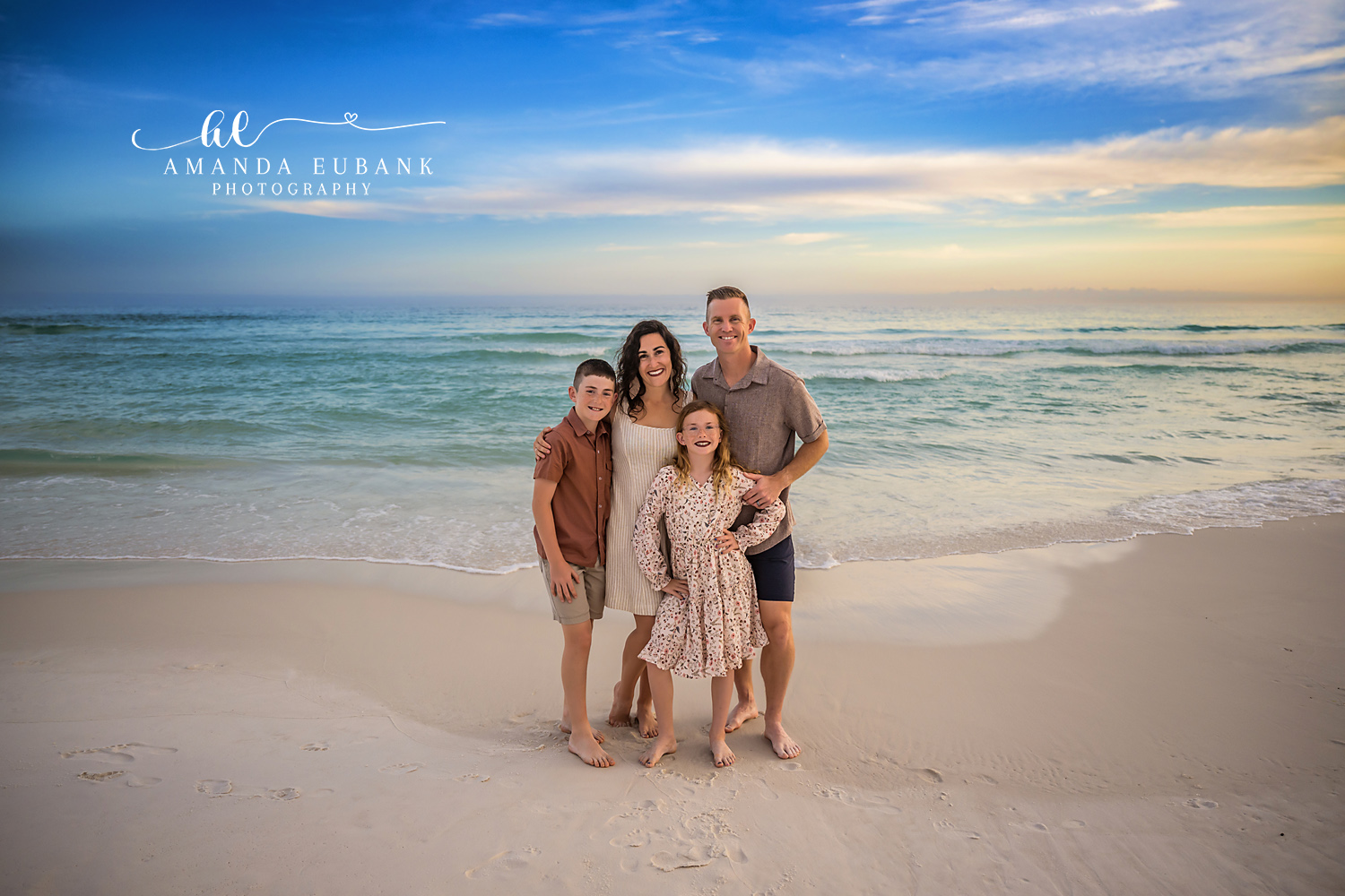 Destin Family of Four Beach Portrait at Henderson Beach State Park | Destin FL Family Photographer Family of four gathered close in coordinated cream sage and rust coastal outfits on the white sand at Henderson Beach State Park in Destin FL with the Gulf behind