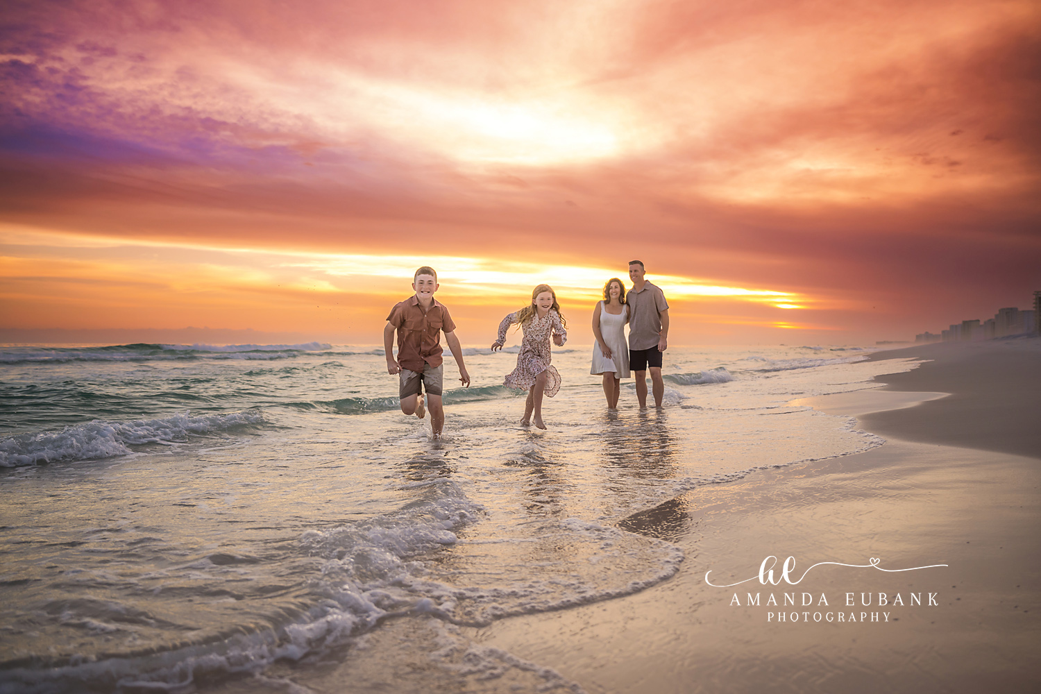 Destin Family Walking in the Surf Golden Hour | Destin FL Family Photographer Family of four walking together through the foamy Gulf surf at Destin FL during golden hour with the sun setting and a fiery orange sky