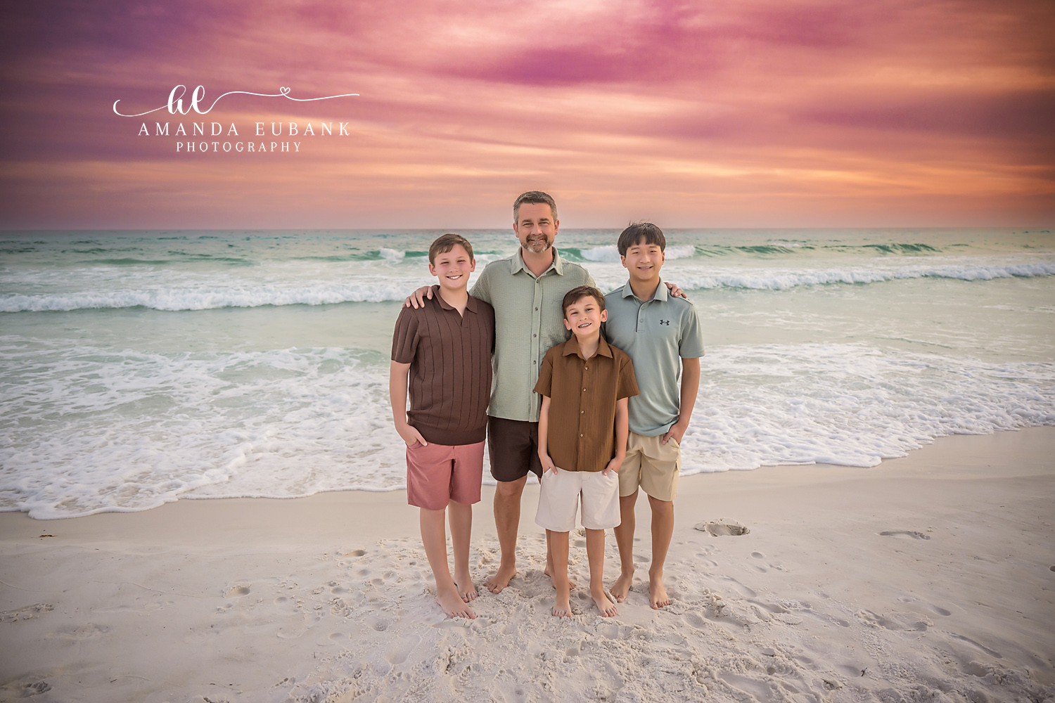 Miramar Beach Father and Sons Sunset Portrait | Miramar Beach FL Family Photographer Father in a sage button up shirt with his three sons in coordinated coastal outfits on Miramar Beach FL at sunset with the Gulf surf and a vivid pink sky