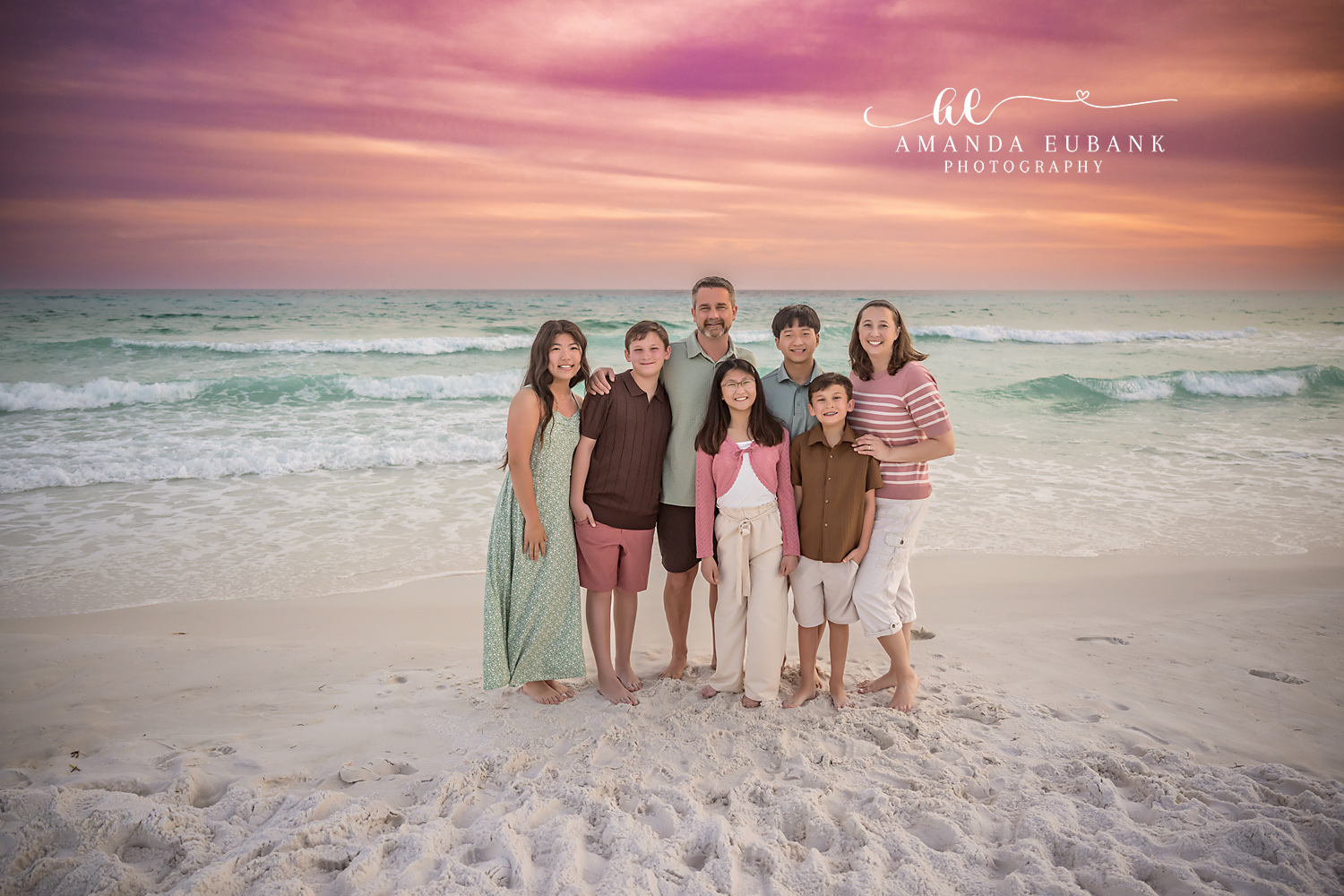 Miramar Beach Family of Seven Sunset Portrait | Miramar Beach FL Family Photographer Family of seven in coordinated sage pink and brown coastal outfits gathered together on Miramar Beach FL at sunset beneath a vivid pink and purple sky