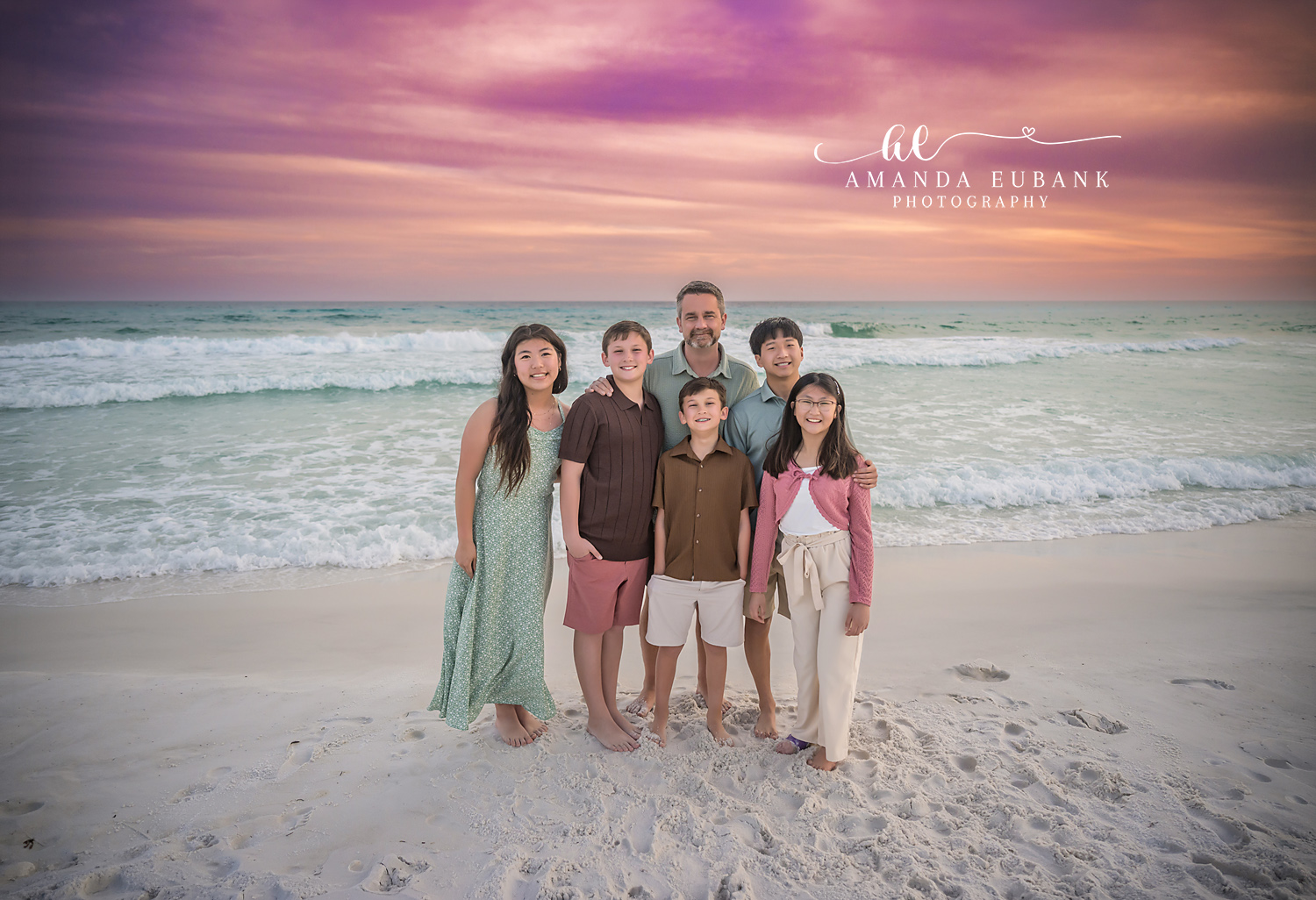 Miramar Beach Father and Five Kids Sunset Portrait | Miramar Beach FL Family Photographer Father with his five children gathered around him on Miramar Beach FL at sunset with the Gulf surf and a vivid pink and purple sky behind them