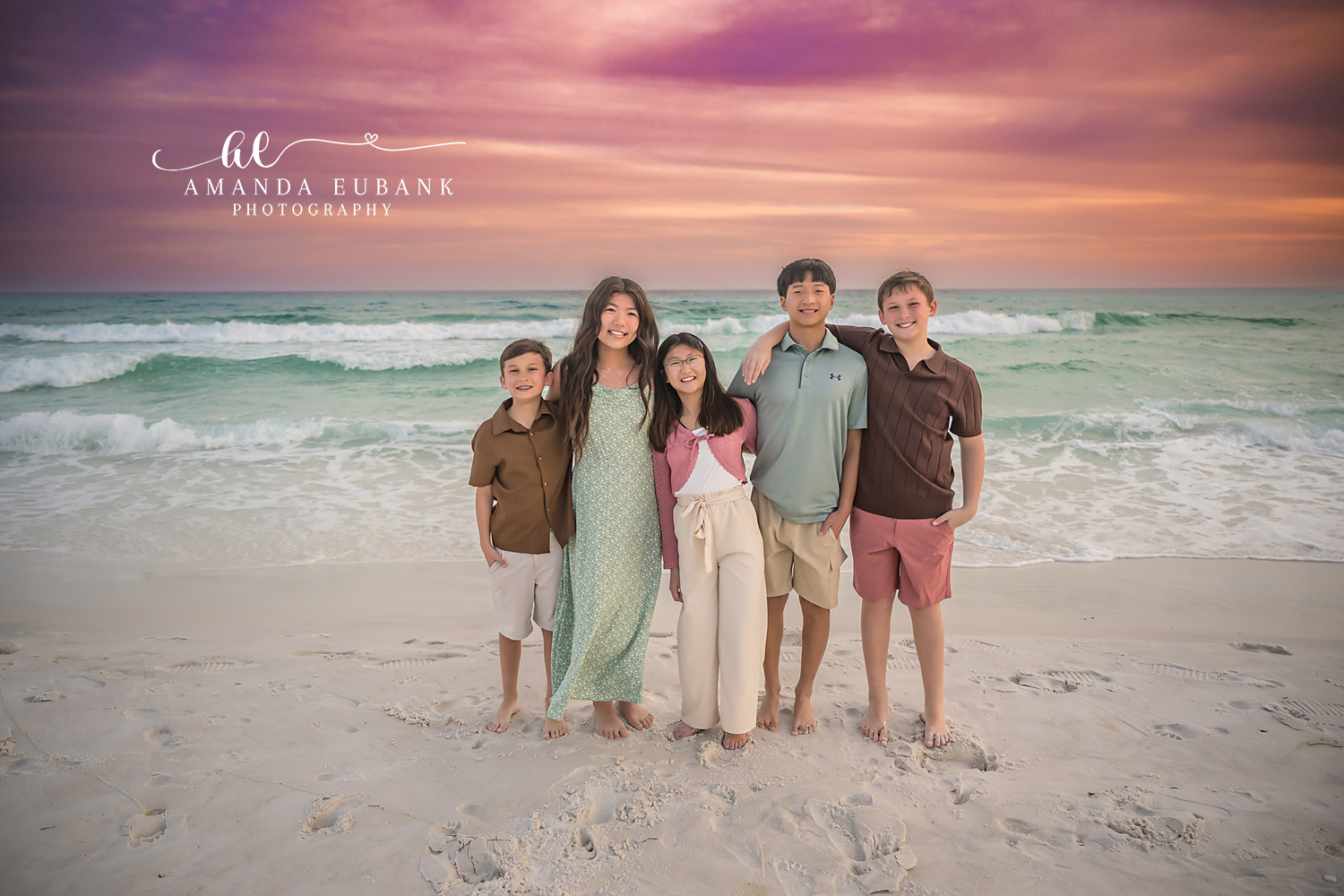 Miramar Beach All Five Siblings Sunset Lineup | Miramar Beach FL Family Photographer All five M family siblings lined up arm in arm on Miramar Beach FL at sunset in coordinated coastal outfits with the Gulf surf and a pink orange sky