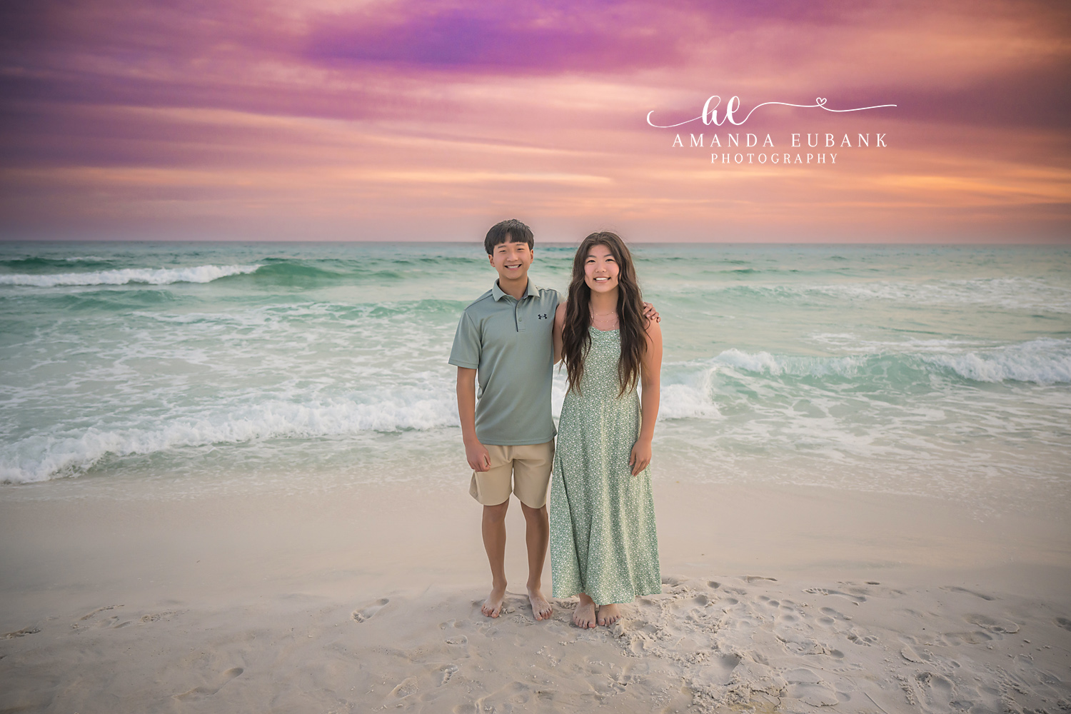 Miramar Beach Big Sister and Brother Sunset Portrait | Miramar Beach FL Family Photographer Older sister in sage green floral dress with her oldest brother in a sage polo on Miramar Beach FL at sunset with the Gulf surf and a pink purple sky