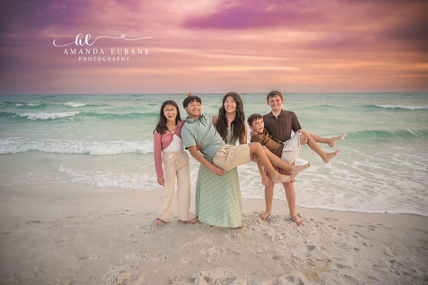 Miramar Beach Siblings Lifting Little Brother Sunset Portrait | Miramar Beach FL Family Photographer Five M family siblings laughing together as the older ones lift their youngest brother in the air on Miramar Beach FL at sunset