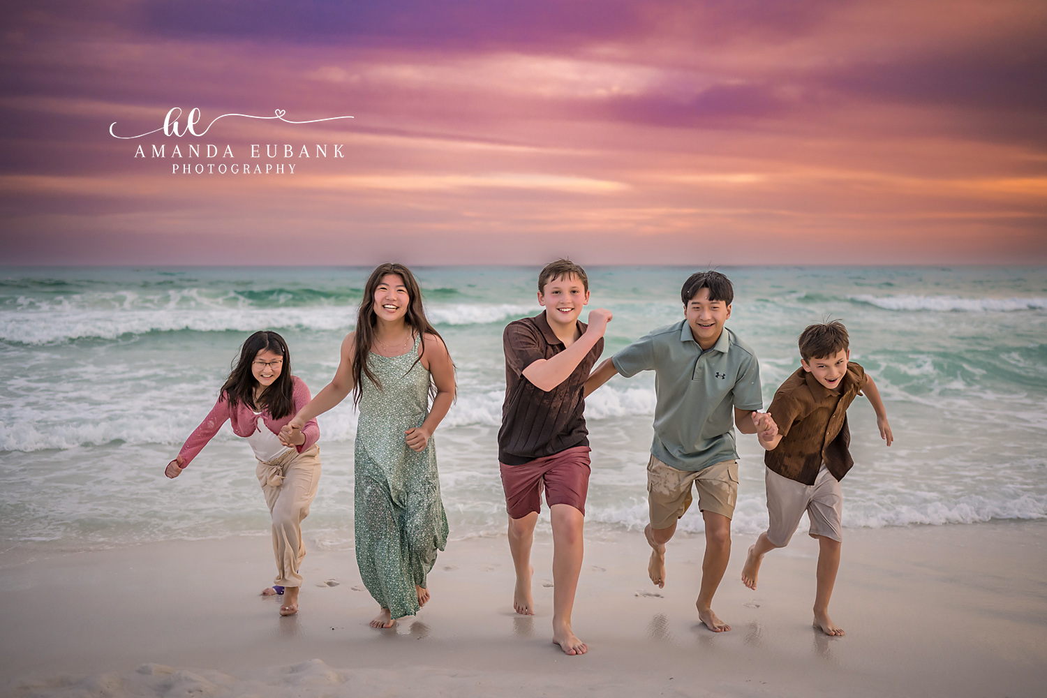 Miramar Beach Siblings Running Along the Shoreline Sunset | Miramar Beach FL Family Photographer Five M family siblings running and laughing together along the Miramar Beach FL shoreline at sunset beneath a soft pink and pastel sky