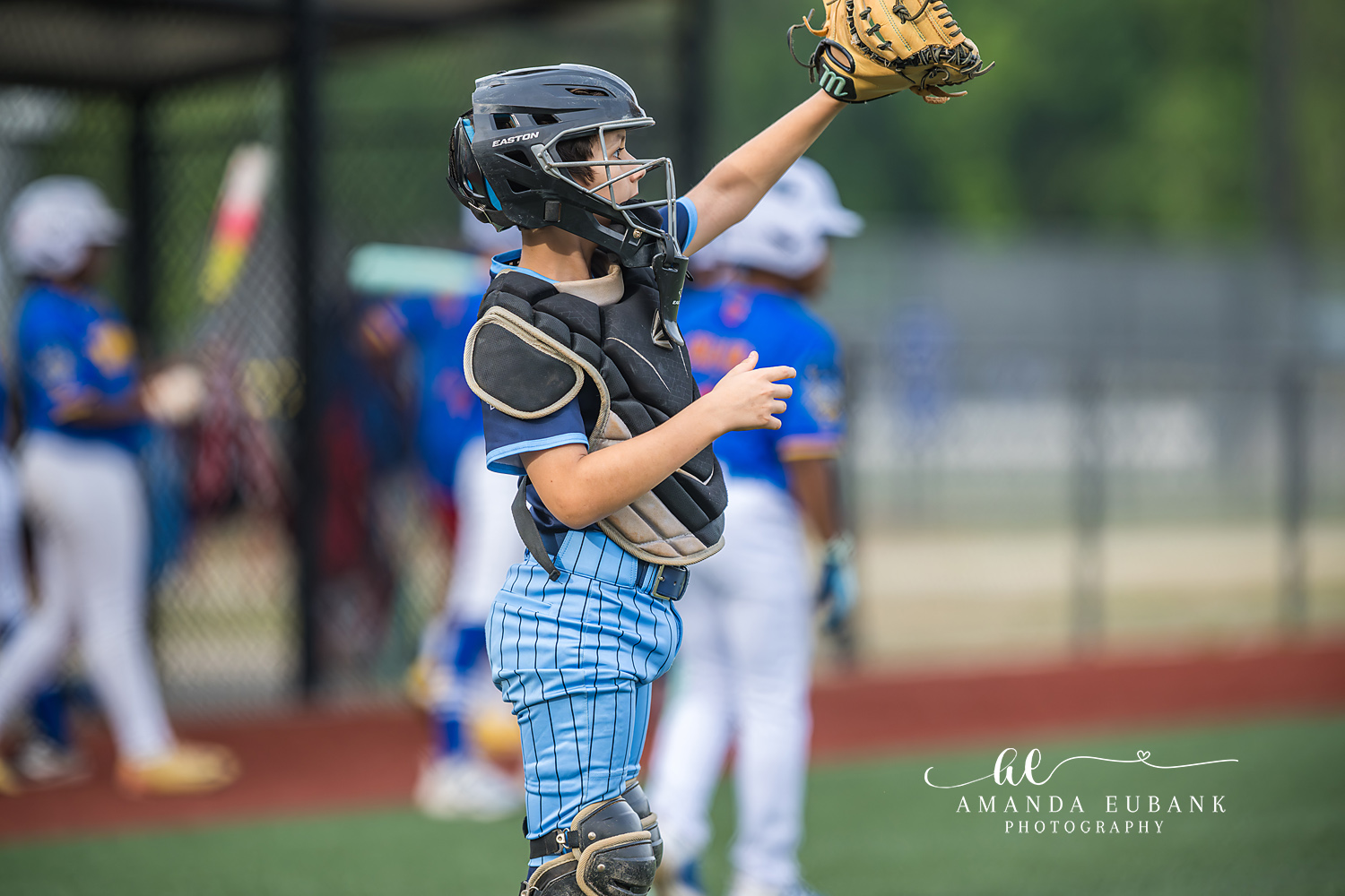 Catcher Catching Pop-Up | Hoover AL Travel Baseball Photographer Youth baseball catcher in full chest protector, helmet, and light blue pinstripe pants reaches his glove high to catch a pop-up during a Kilcrease 11U tournament game in Hoover, Alabama.