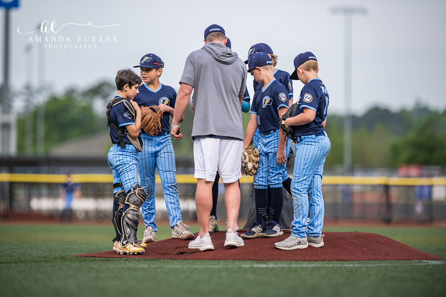 Coach Mound Visit Huddle | Hoover AL Travel Baseball Photographer A coach in a gray hoodie meets with five Power Kilcrease 11U players — the catcher in full gear and four infielders — for a mound visit during a Hoover, Alabama tournament game.