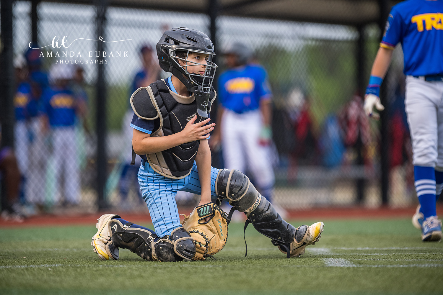 Catcher Resting Between Plays | Hoover AL Travel Baseball Photographer Power Kilcrease 11U catcher takes a knee in full gear with hand to chest, gathering himself between plays during a Hoover, Alabama tournament game with the opposing royal blue team in the background.