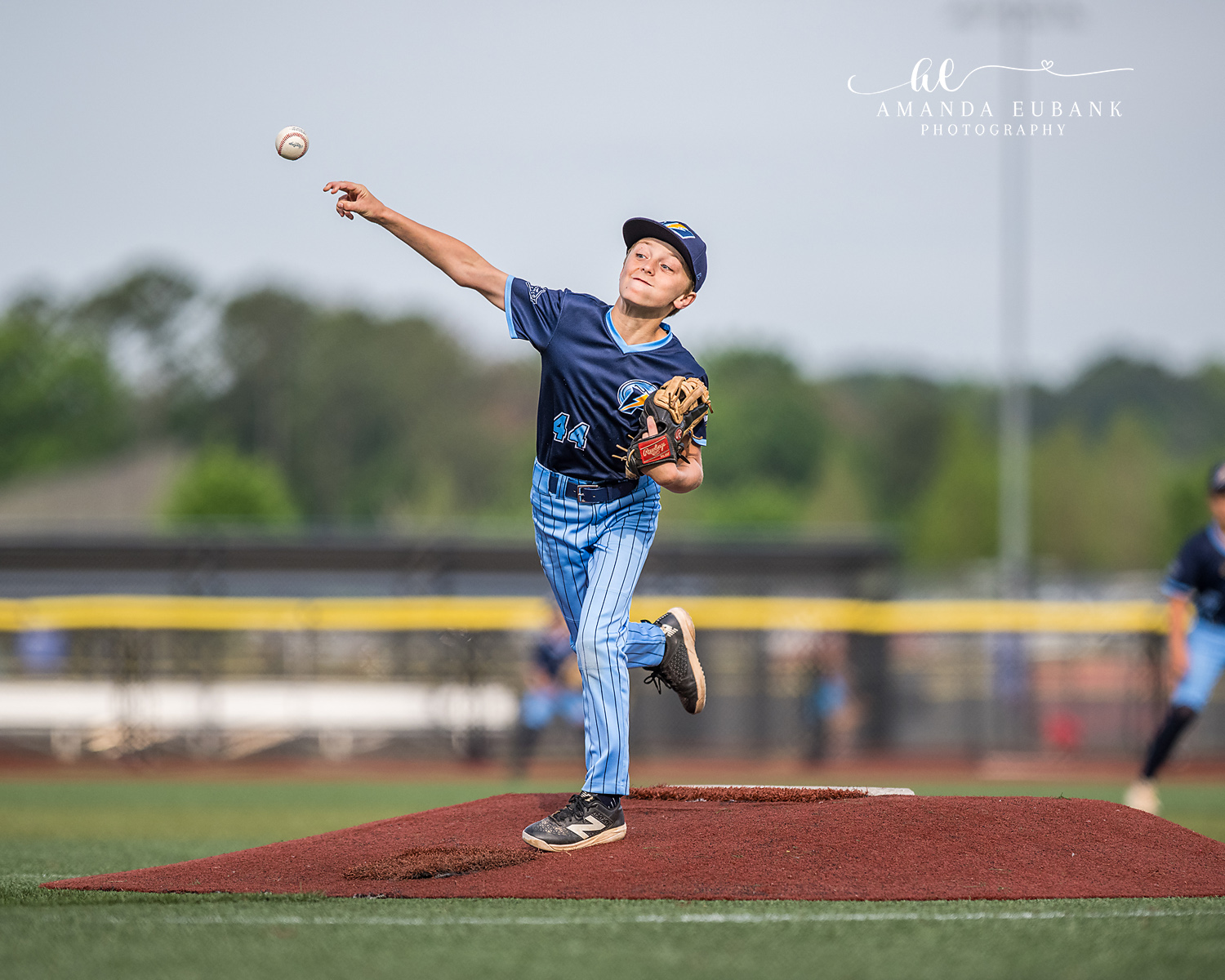 Lefty Pitcher Number 14 Follow-Through | Hoover AL Travel Baseball Photographer Power Kilcrease 11U left-handed pitcher number 14 finishes his follow-through on the red dirt mound as the released ball floats above his outstretched arm during a Hoover, Alabama tournament game.