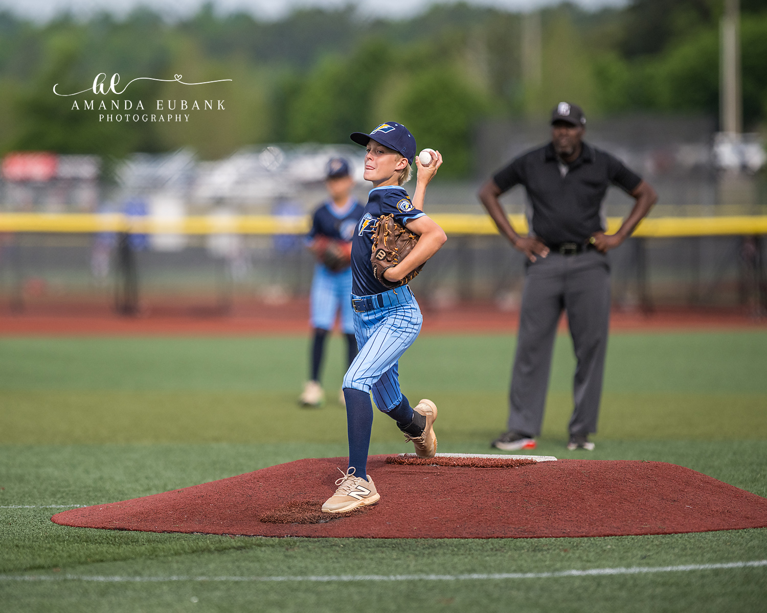 Pitcher Loaded with Umpire Watching | Hoover AL Travel Baseball Photographer Power Kilcrease 11U pitcher reaches the loaded position on the red dirt mound with the umpire standing nearby hands on hips during a Hoover, Alabama tournament game.