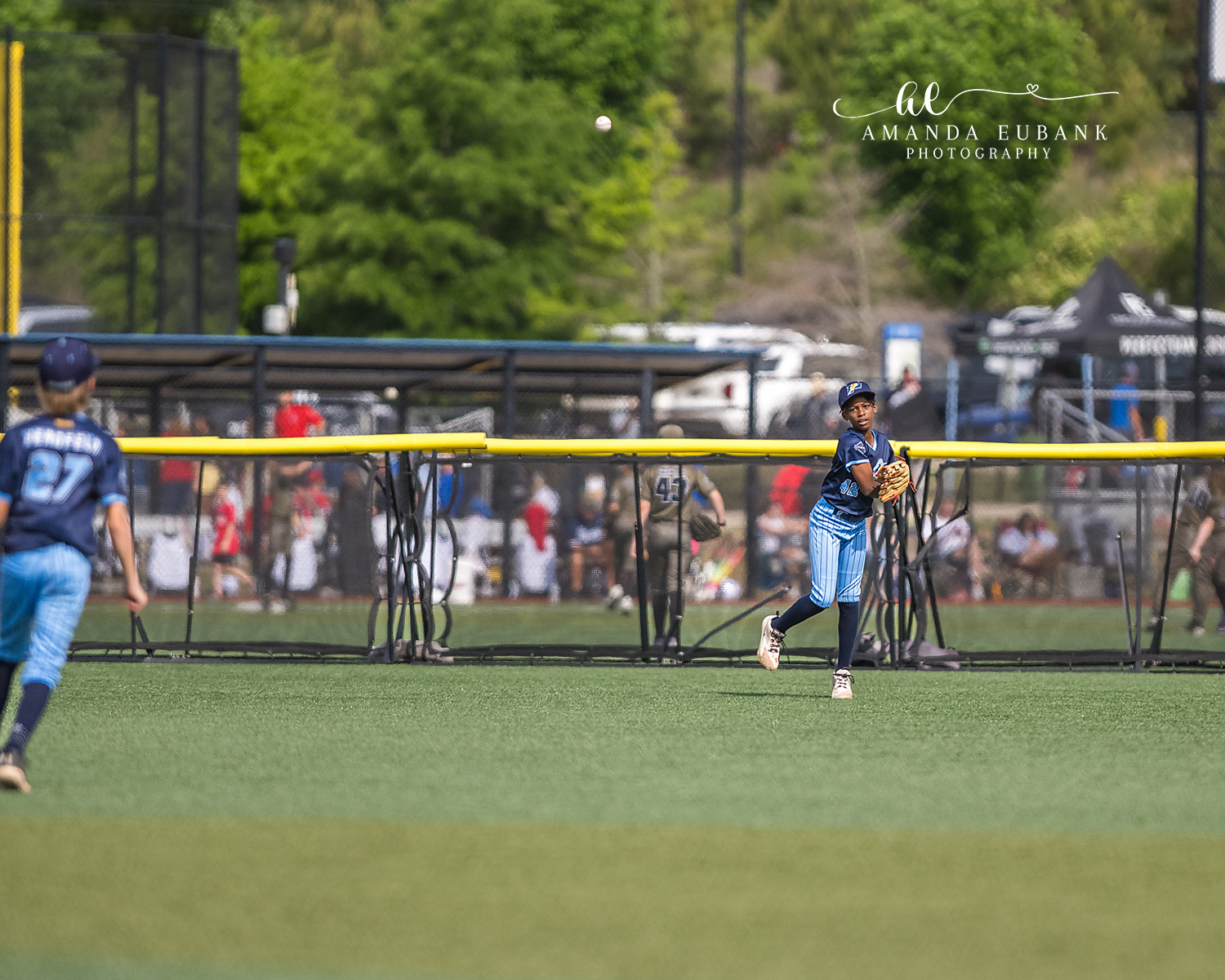 Outfielder Throw In With Ball Mid-Air | Hoover AL Travel Baseball Photographer Power Kilcrease 11U outfielder finishes a long throw back to the infield with the baseball visible high in the air during a Hoover, Alabama tournament game, teammate Beauford trailing behind.
