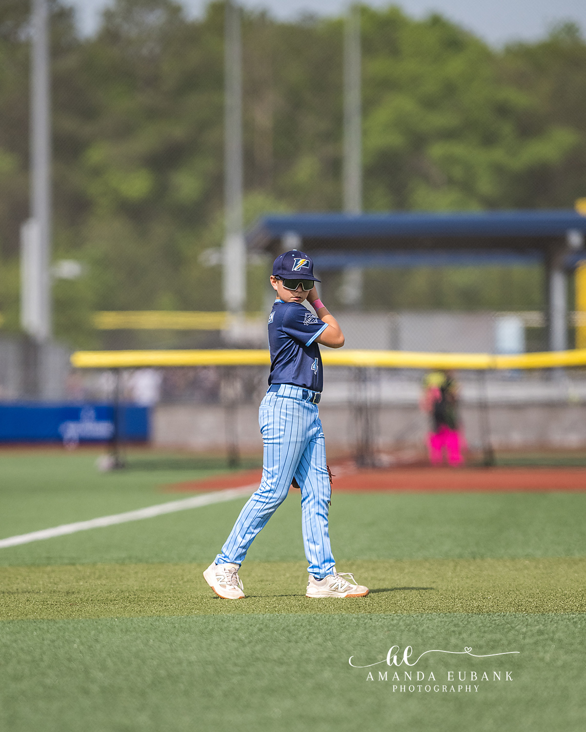 Outfielder Solo Walk Glove Up | Hoover AL Travel Baseball Photographer Power Kilcrease 11U outfielder walks across the green grass with glove raised near his face during a Hoover, Alabama tournament game, captured solo with the field stretching behind him.