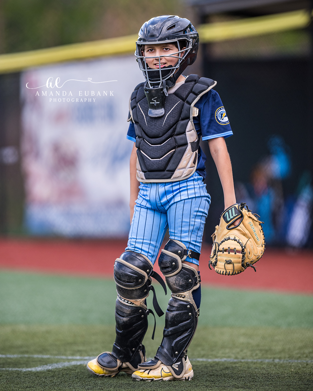 Catcher Full Gear Hero Portrait | Hoover AL Travel Baseball Photographer Power Kilcrease 11U catcher stands full-length in his Easton helmet, chest protector, leg guards, light blue pinstripe pants, and tan Wilson mitt during a Hoover, Alabama tournament game.