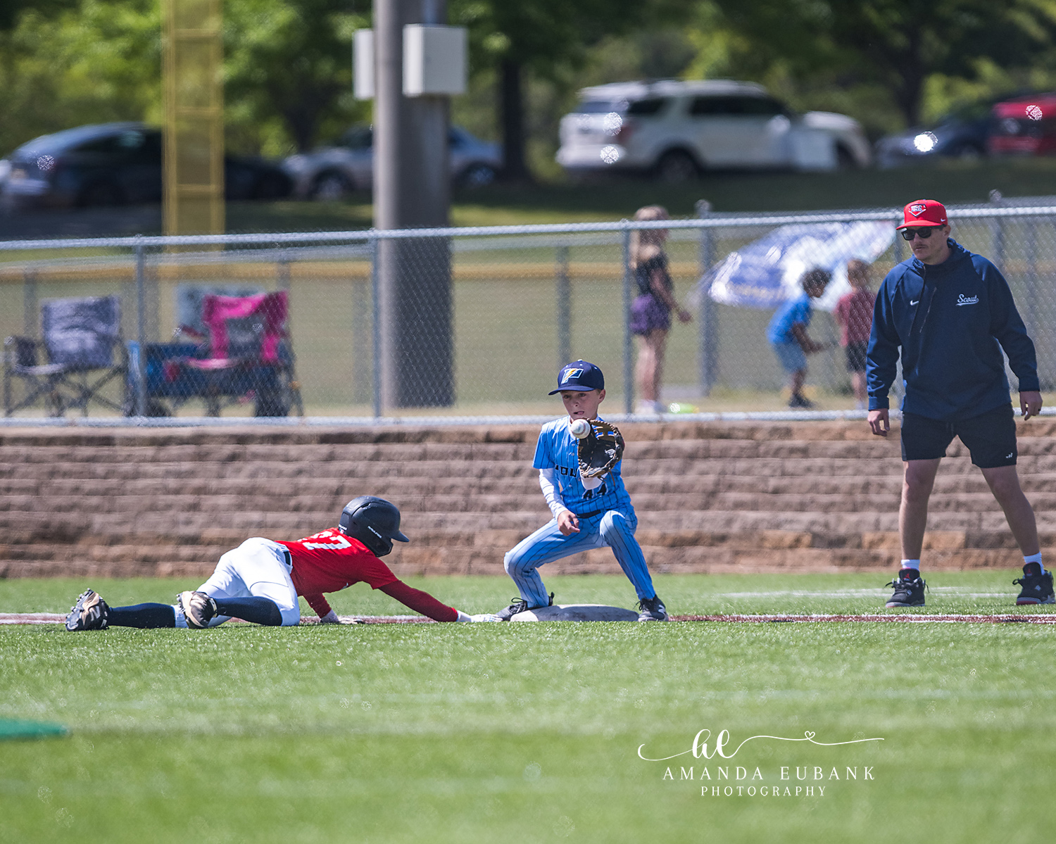Pickoff Tag at Second Base | Hoover AL Travel Baseball Photographer Power Kilcrease 11U infielder catches the ball at the bag as a red-jersey opposing baserunner slides headfirst into second base during a Hoover, Alabama tournament game, the coach watching from behind.