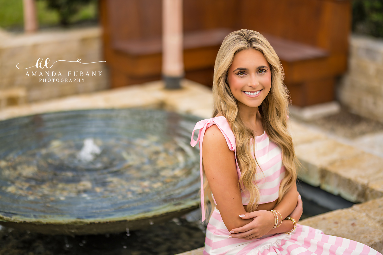 Stone Fountain Senior Portrait in Alys Beach | Photographer in Alys Beach Senior in a pink-striped two-piece seated on a stone Alys Beach fountain, by Photographer in Alys Beach Amanda Eubank.