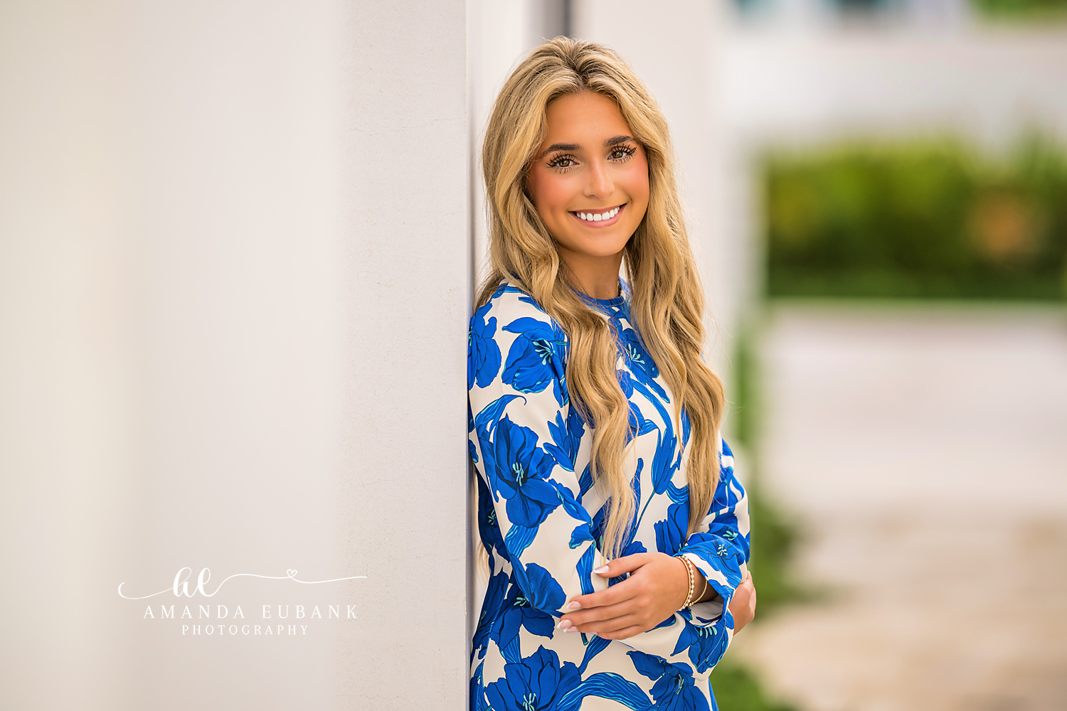 Bright Senior Close-Up by White Wall | Photographer in Alys Beach Close-up of a smiling senior in blue floral maxi against a white Alys Beach wall, by Photographer in Alys Beach Amanda Eubank.