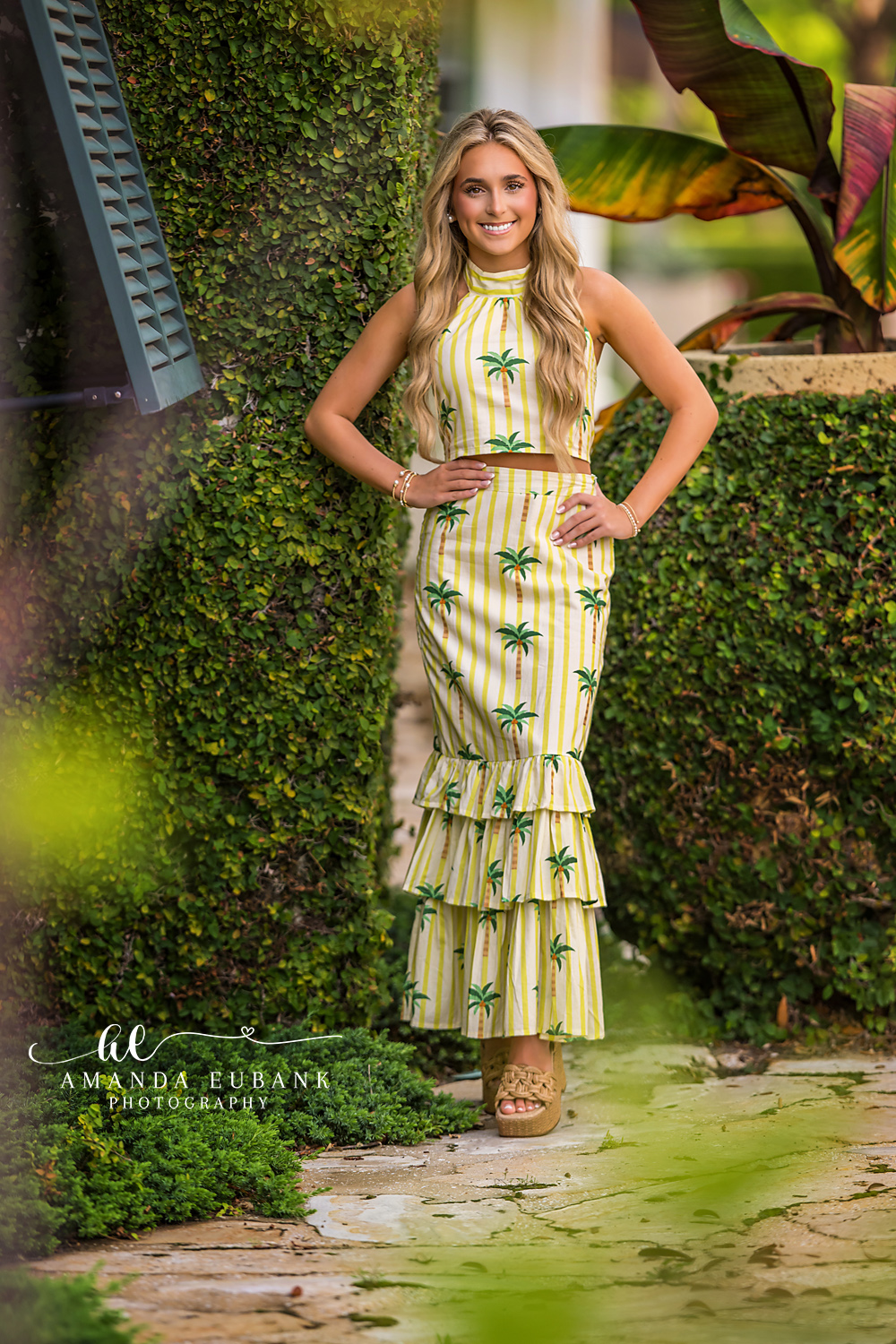 Ivy Wall Senior Portrait | Senior Photographer in Alys Beach Senior in a palm-print outfit by an ivy-covered Alys Beach wall and tropical foliage, by Senior Photographer in Alys Beach Amanda Eubank.