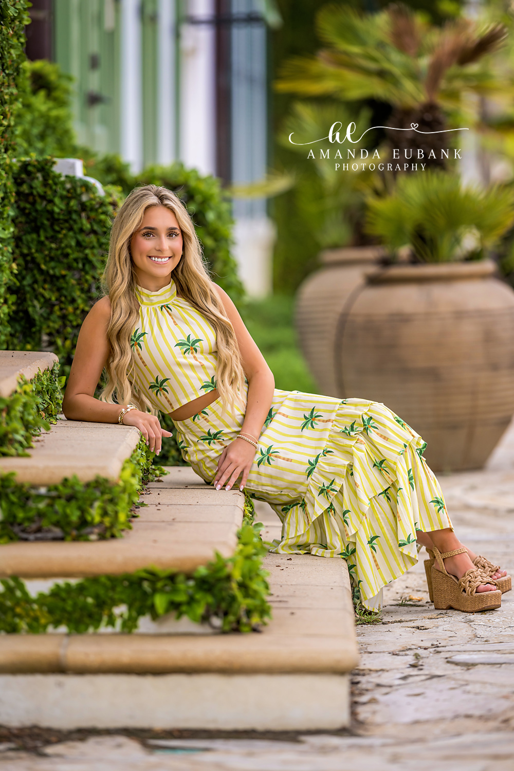 Tropical Garden Senior Session in Alys Beach | Alys Beach Photographer Senior smiling in a palm-print outfit by terracotta planters in an Alys Beach garden, by Alys Beach Photographer Amanda Eubank.
