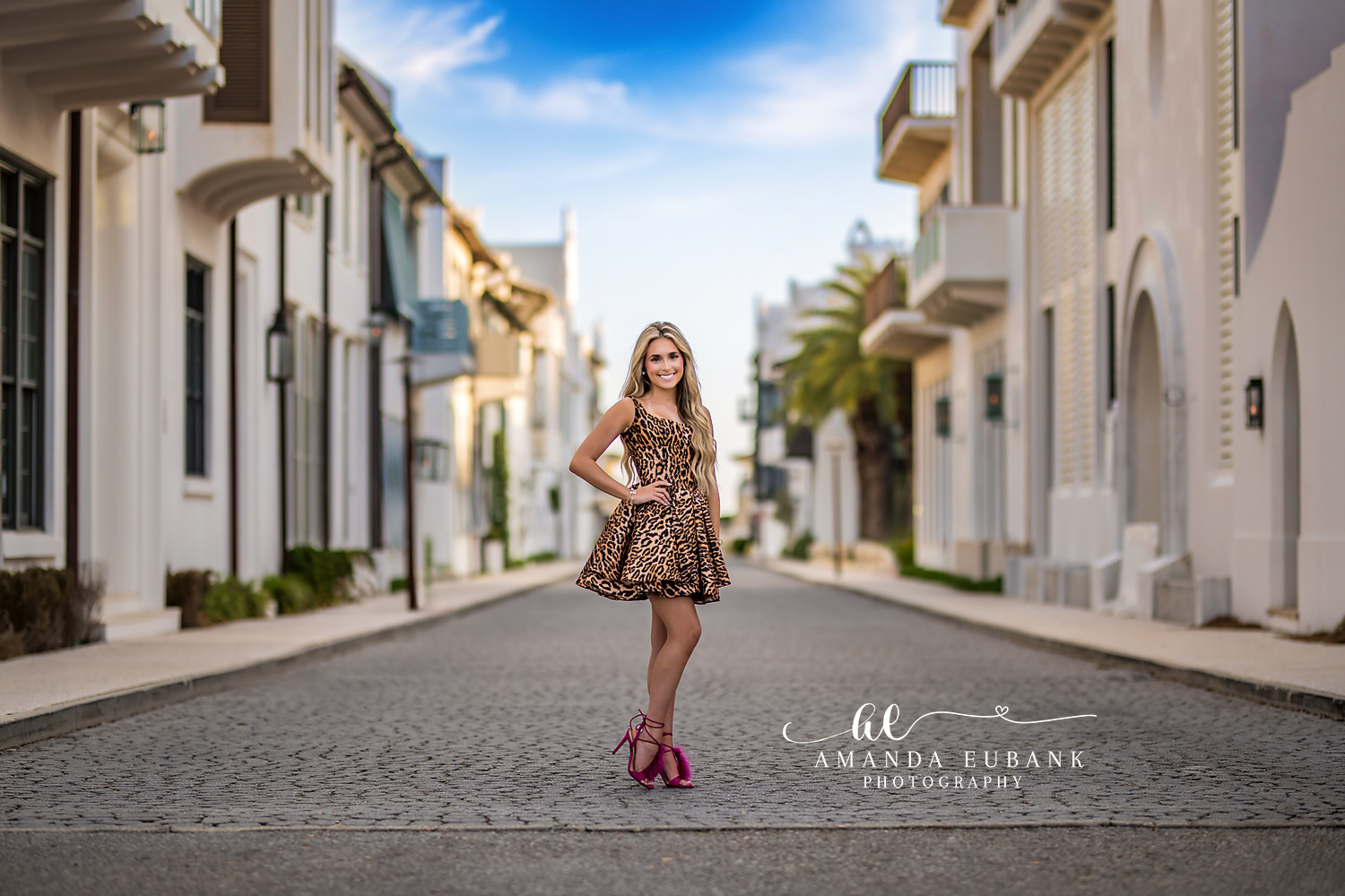 Confident Senior Pose on Alys Beach Brick Street | Alys Beach Photographer Senior posing confidently on a brick Alys Beach street between white buildings, by Alys Beach Photographer Amanda Eubank.