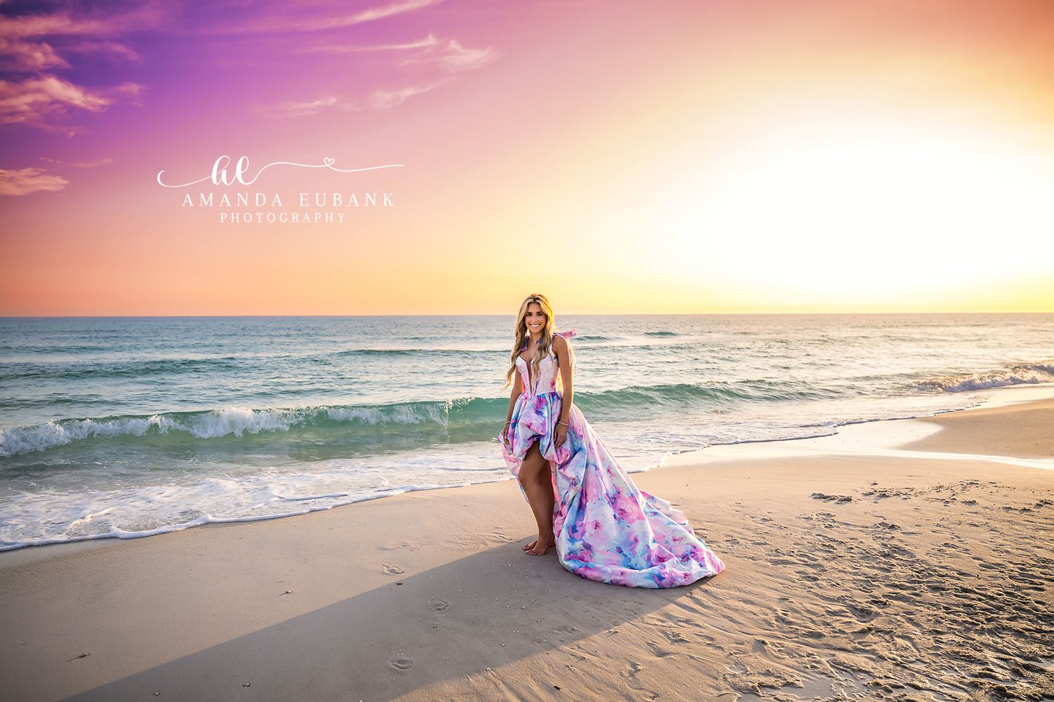 Senior Portrait at the Water’s Edge in Watercolor Gown | Alys Beach Senior Photographer Senior in a pastel watercolor high-low gown with flowing train at the water's edge as a wave rolls in at sunset, by Alys Beach Senior Photographer Amanda Eubank.