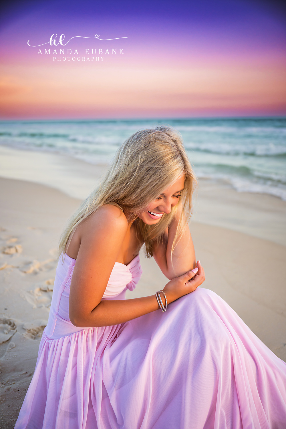 Rosemary Beach Candid Laughter Senior Portrait | 30A Senior Photographer Senior girl in a blush pink gown laughing softly while kneeling on the Rosemary Beach shoreline at sunset