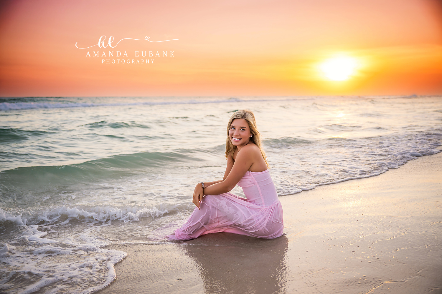 Rosemary Beach Sunset Shoreline Senior Portrait | 30A Senior Photographer High school senior in a flowing blush pink gown sitting at the water's edge as the sun sets over the Gulf in Rosemary Beach FL on 30A