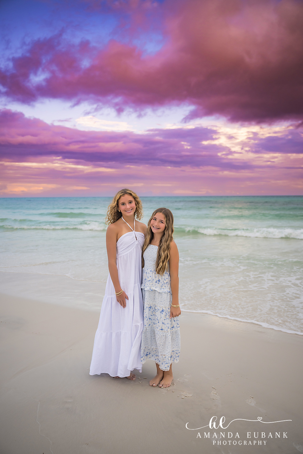 30A Family Photographer – Mother and Daughter in Santa Rosa Beach Two girls in white dresses on the wet sand at Seagrove Beach during a purple 30A sunset