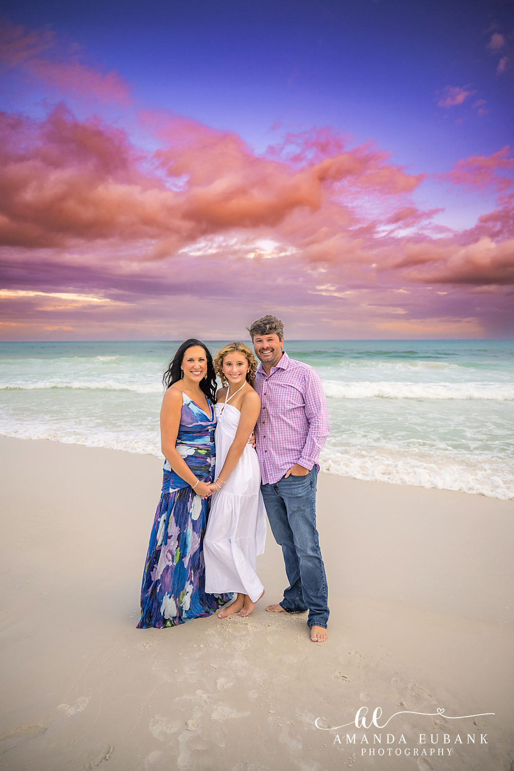 30A Family Photographer – Vertical Beach Portrait at Sunset 30A family photographer portrait of three on Seagrove Beach with pink clouds overhead