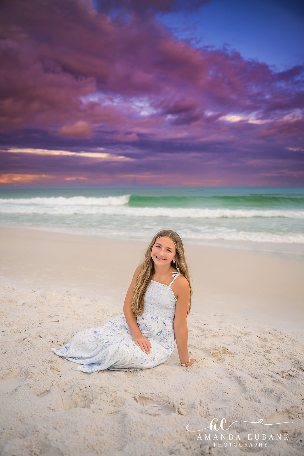 Santa Rosa Beach Teen Portrait at Sunset on 30A Young girl in a blue and white dress sitting on the sand during a 30A sunset session