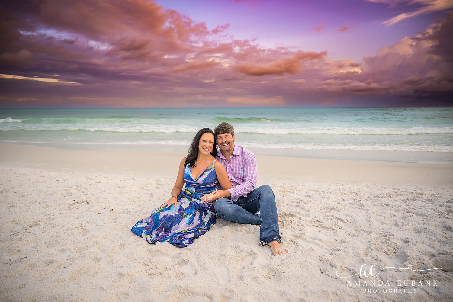 30A Couples Photographer – Seated Beach Portrait at Sunset Couple seated on the sand at Seagrove Beach beneath a violet and rose 30A sunset
