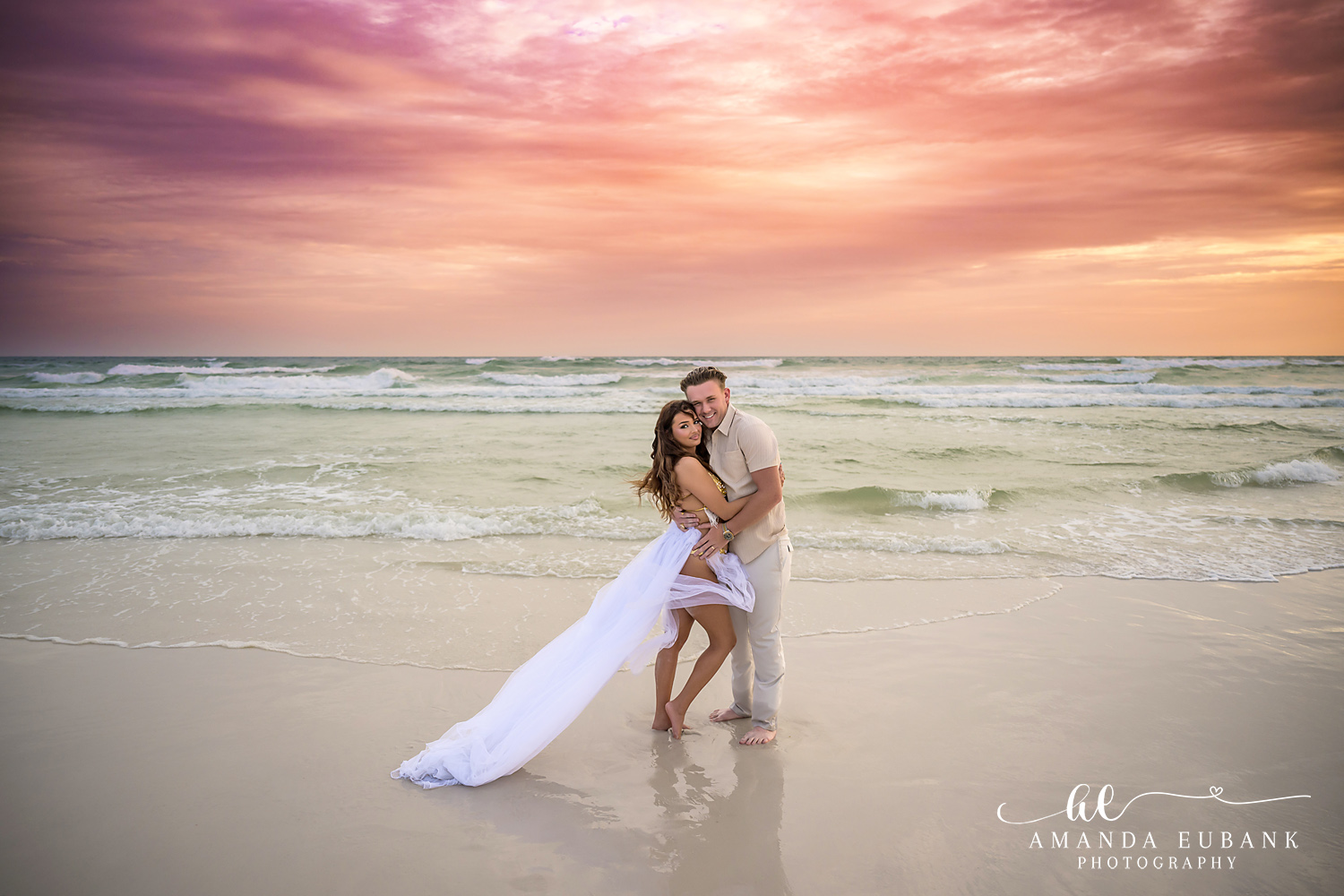 30A Couples Photos – Flowing White Dress at Dune Allen Beach Couple embracing at the waterline as a long white tulle skirt trails across the wet sand