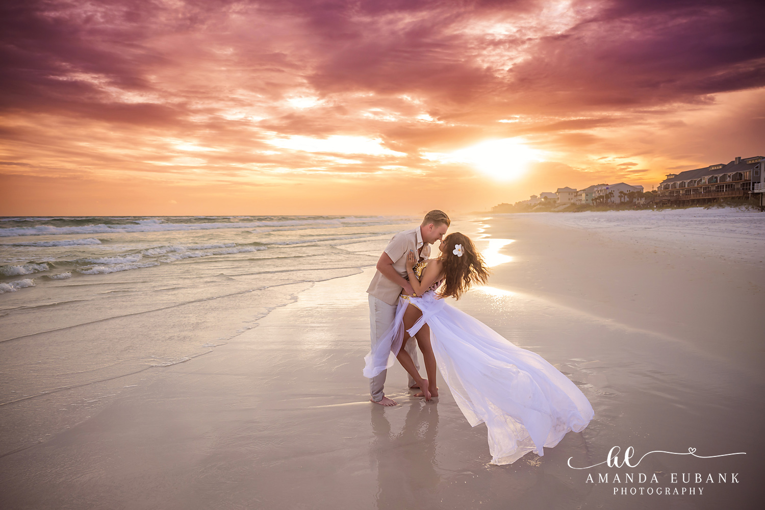 30A Sunset Dip Kiss with the Gulf Behind – Dune Allen Beach Couple kissing on the shoreline with the Dune Allen beach houses and sunset behind them