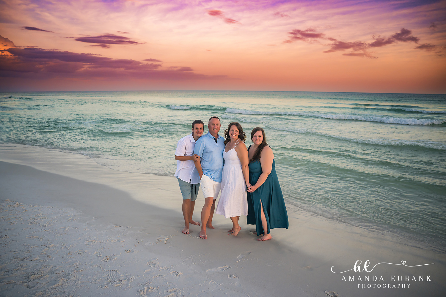 Destin Family Photographer – Family Portrait by the Gulf Family of four posing together by the Gulf in Destin, Florida