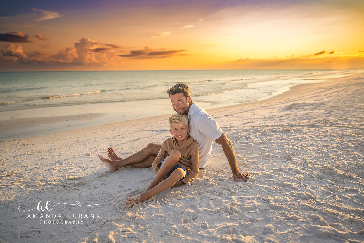 Destin Beach Family Session – Father and Son Playing in the Sand Father and young son playing together in the sand at sunset during a Destin beach family photography session