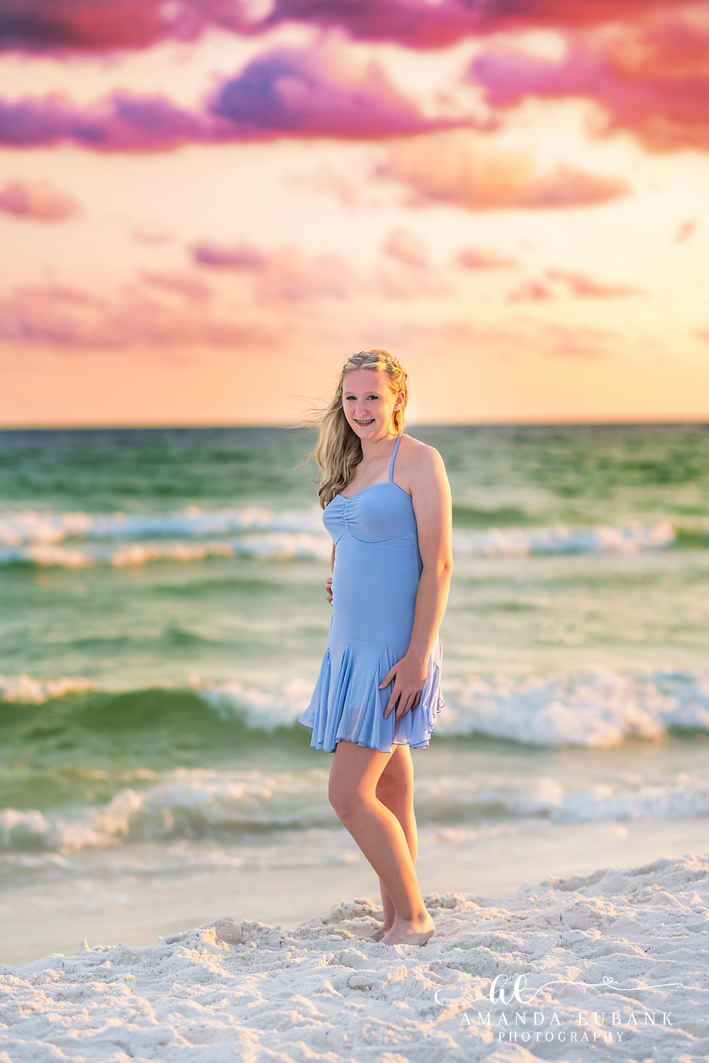 Destin Beach Portrait of a Teen Girl at the Water’s Edge Girl in a periwinkle dress at the Destin waterline with a gold and pink sunset behind her