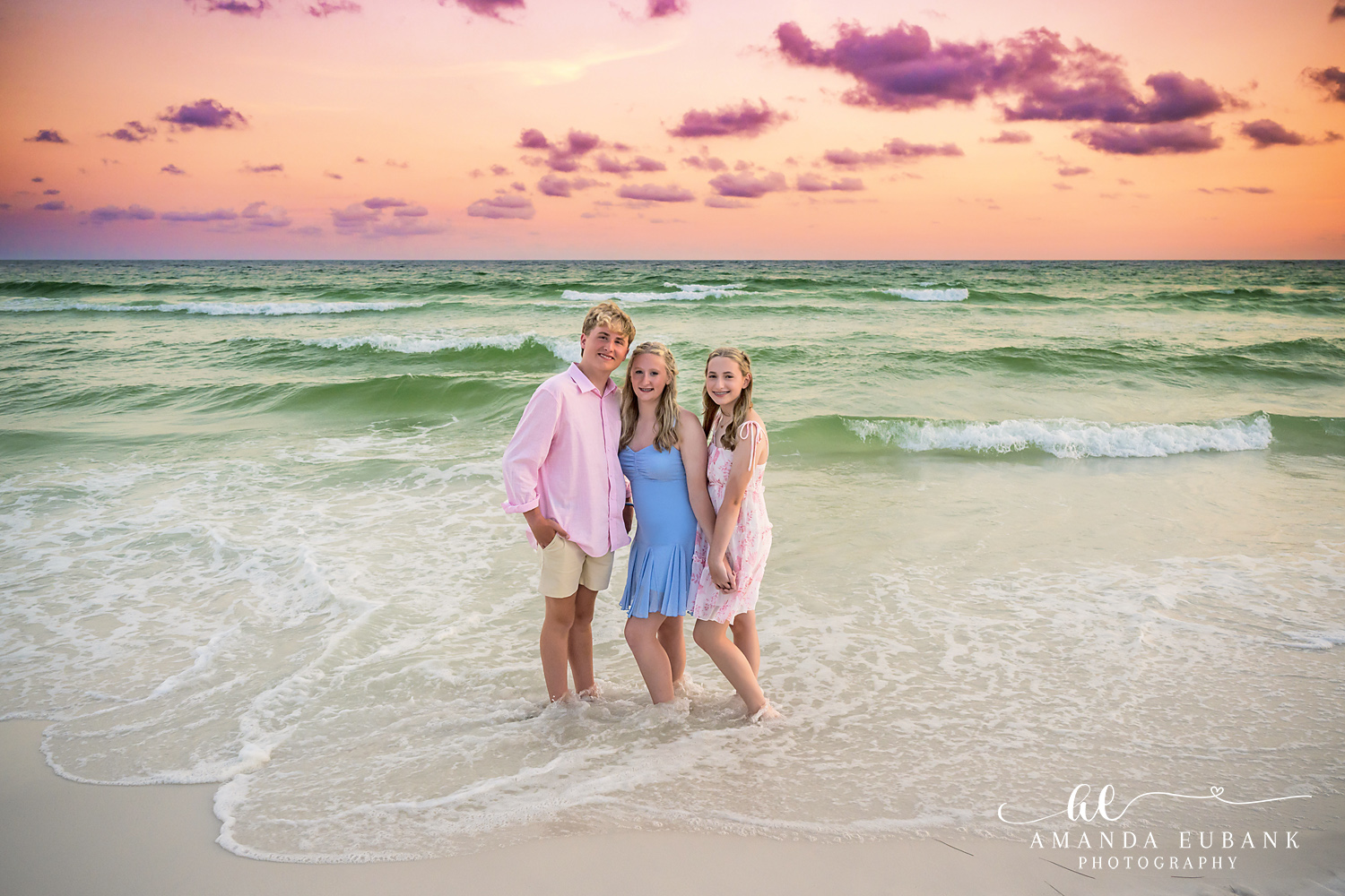 Destin Family Beach Photographer – Three Generations in the Waves Three family members laughing in the shallow water during a Destin sunset beach session