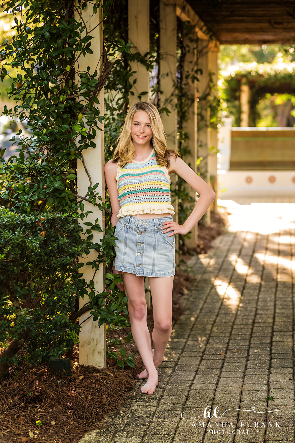 Rosemary Beach Senior Photographer – Shaded Trellis Walkway Portrait Senior girl in a striped top standing in a shaded garden trellis walkway in Rosemary Beach, Florida
