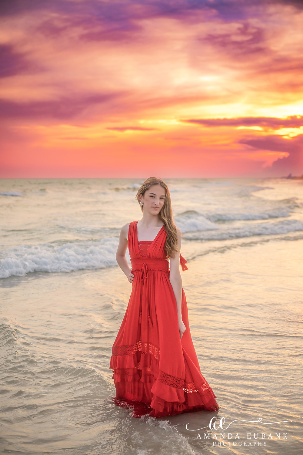 Rosemary Beach Senior Photographer – Golden Sunset Silhouette Senior girl in a red dress standing in the water under a golden sunset sky in Rosemary Beach, Florida