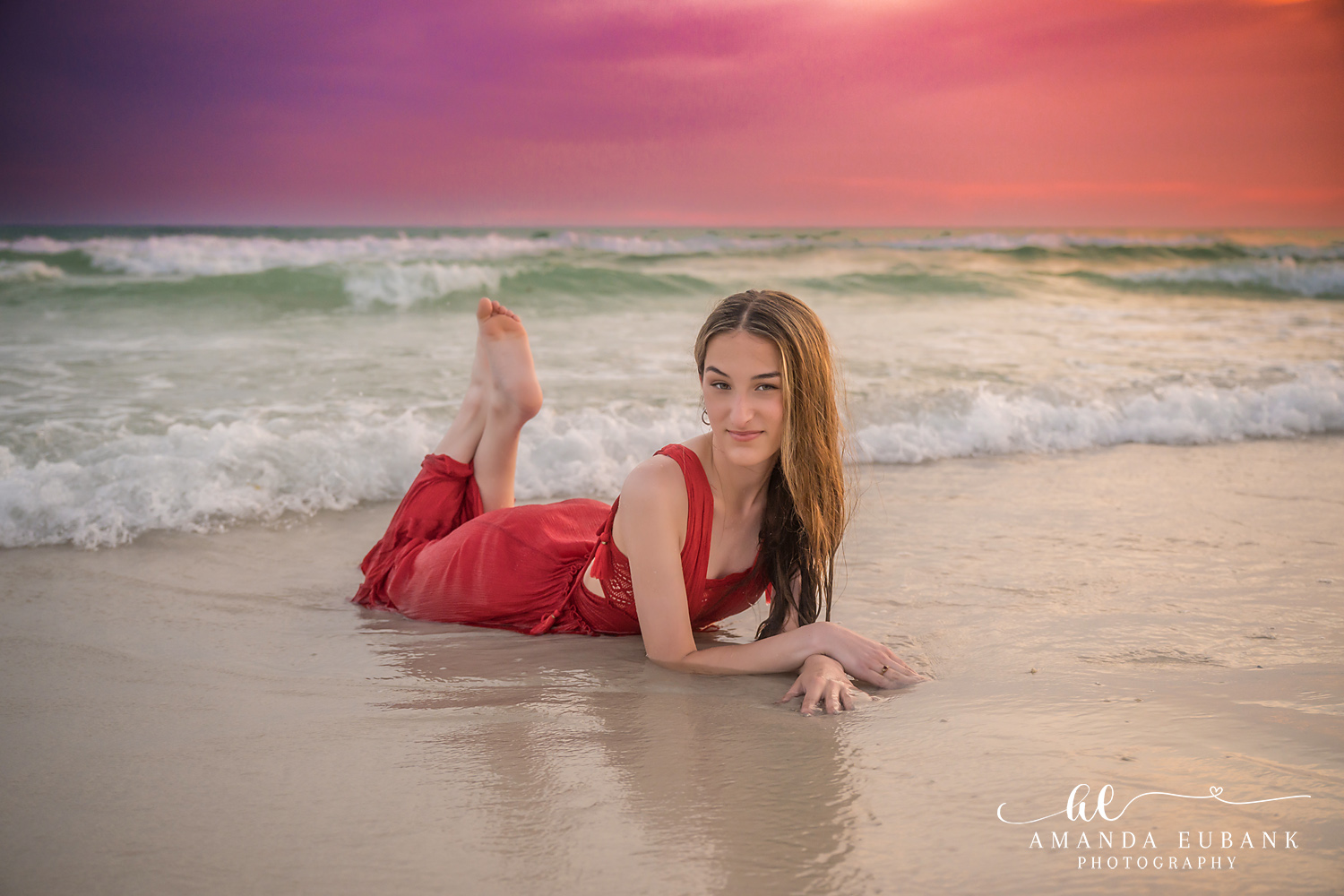 Rosemary Beach Senior Photographer – Red Dress in the Shallow Waves Senior girl lying in shallow ocean water in a red dress at sunset in Rosemary Beach, Florida