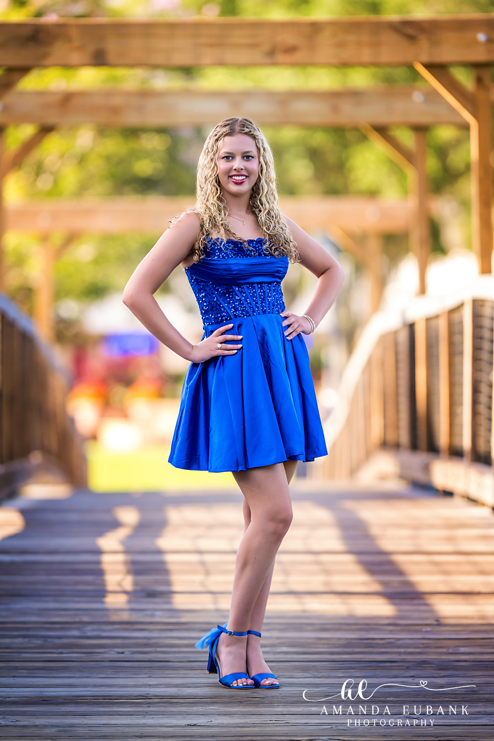 Sandestin Senior Photographer – Confident Pose on the Boardwalk High school senior standing confidently on a boardwalk bridge in a blue dress in Sandestin, Florida