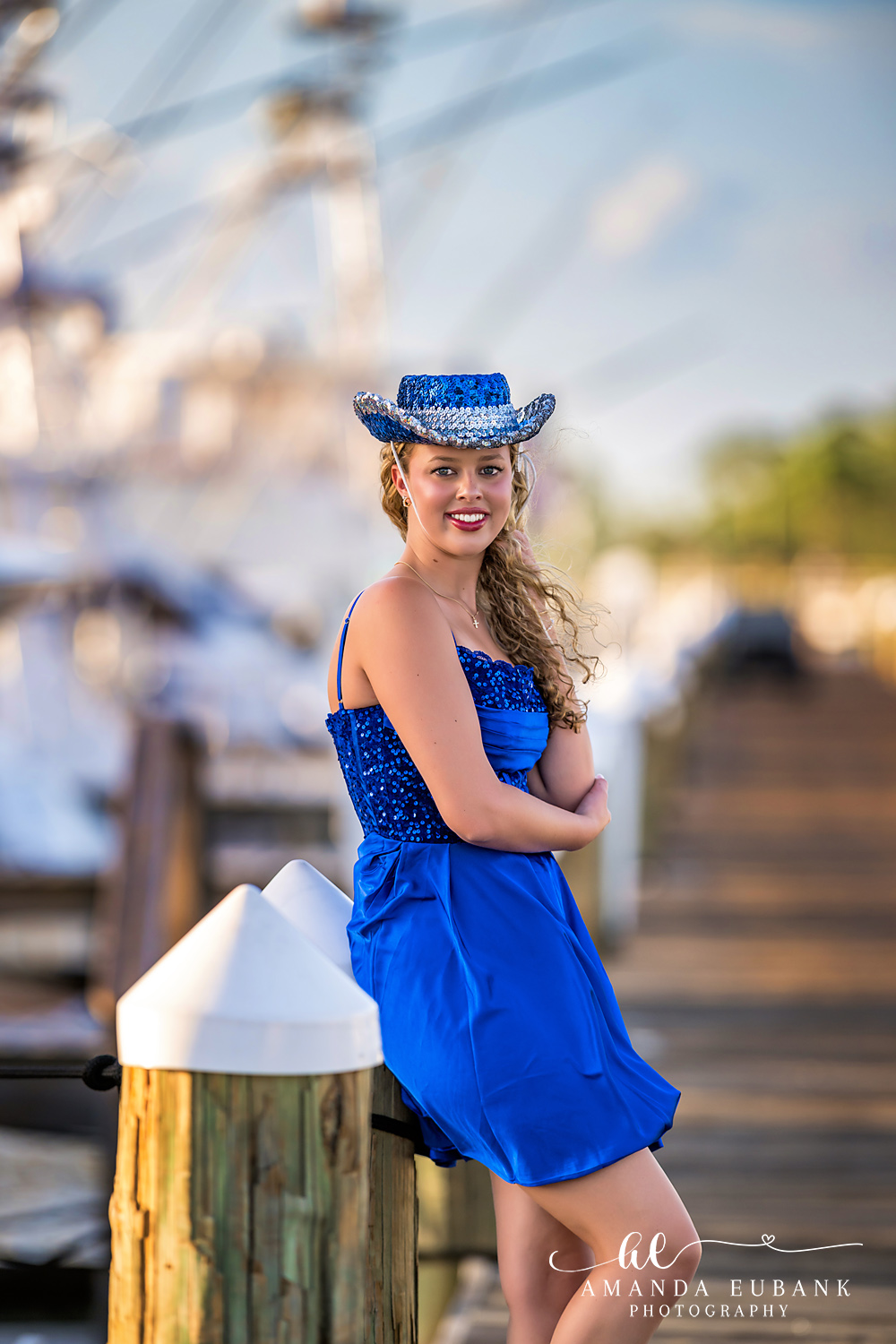 Sandestin Senior Photographer – Off-Shoulder Dress in the Dunes Senior in an off-shoulder blue dress and sun hat standing in the sand dunes in Sandestin, Florida