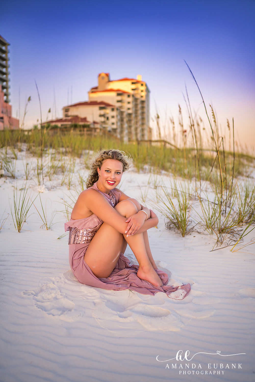 Sandestin Senior Photographer – Seated Among the Sea Oats Senior girl sitting among sea oats in a pink dress in Sandestin, Florida
